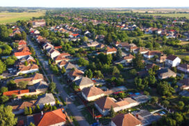 Aerial drone view of a peaceful rural village, traditional houses, red rooftops, and straight streets surrounded by lush greenery and open farmland. Eastern-European village. Balkan village. Hungary.